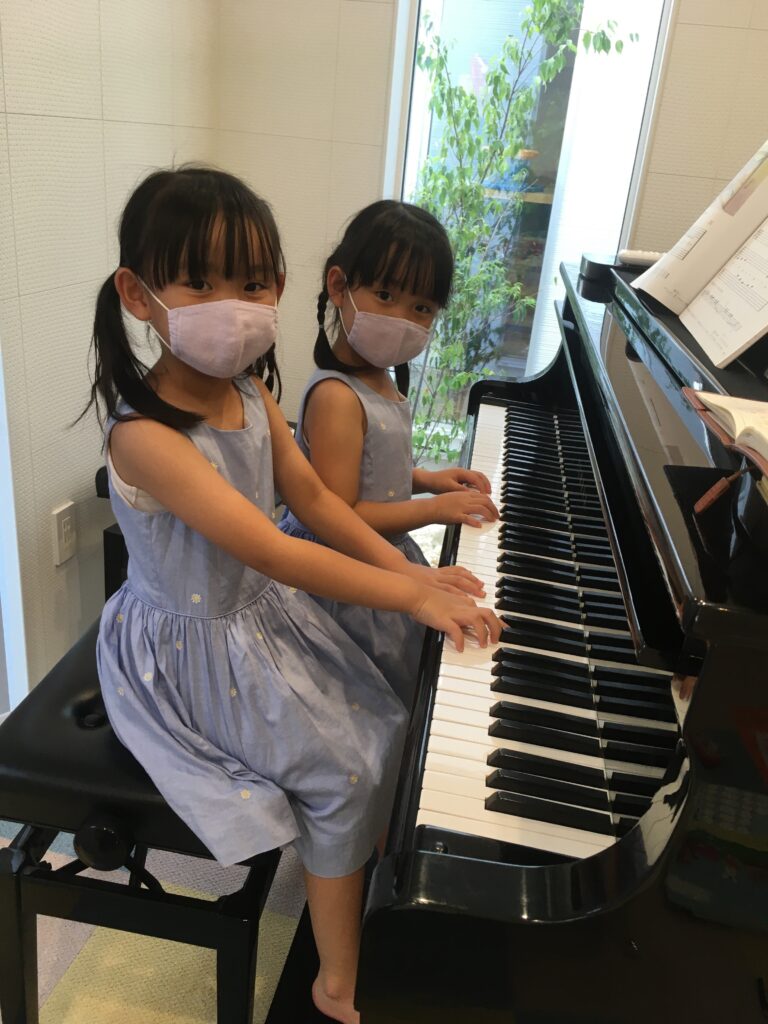 黒いピアノを弾く女の子2人