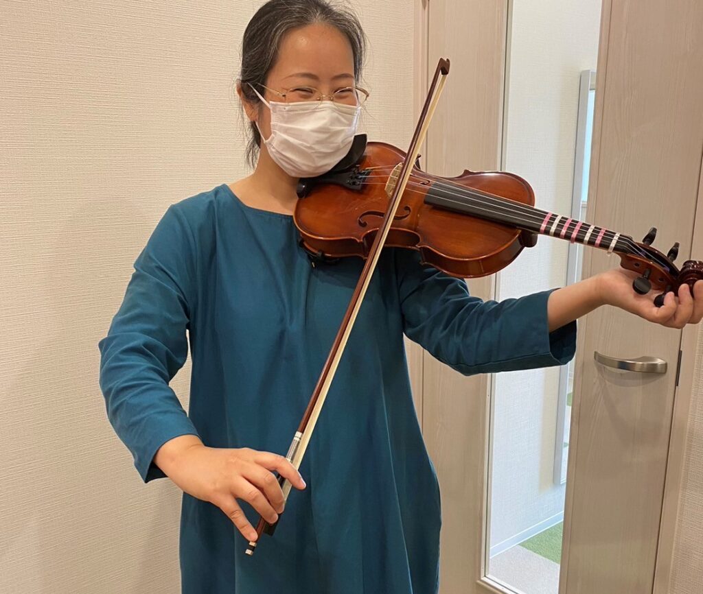 バイオリンを弾く青いワンピースを着た女性