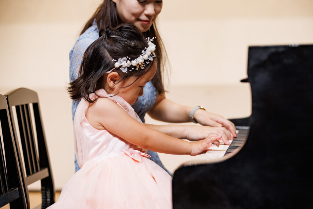 ピンクのドレスを着てピアノを演奏する女の子と先生