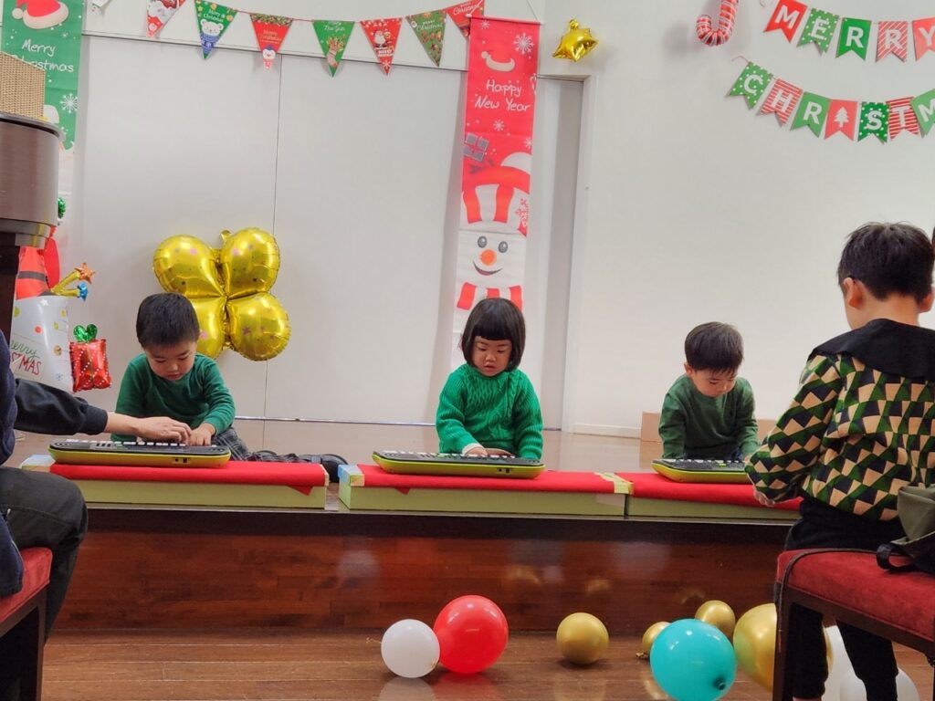 キーボードを演奏する緑の洋服を着た３人の子供