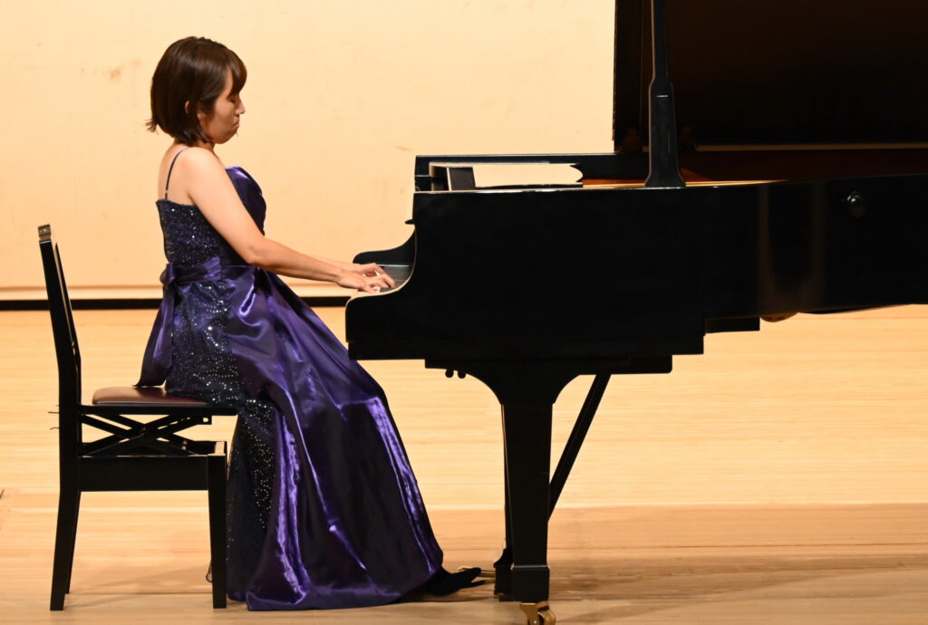 青いドレスを着てピアノを弾く女性